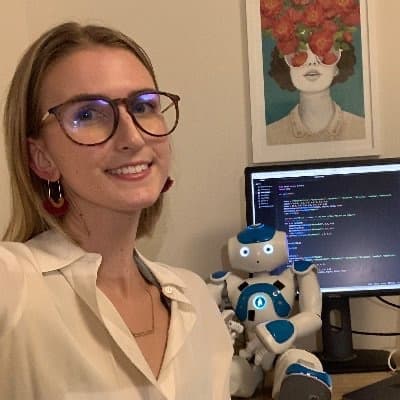 Tess Flanagan beside a humanoid robot at her desk